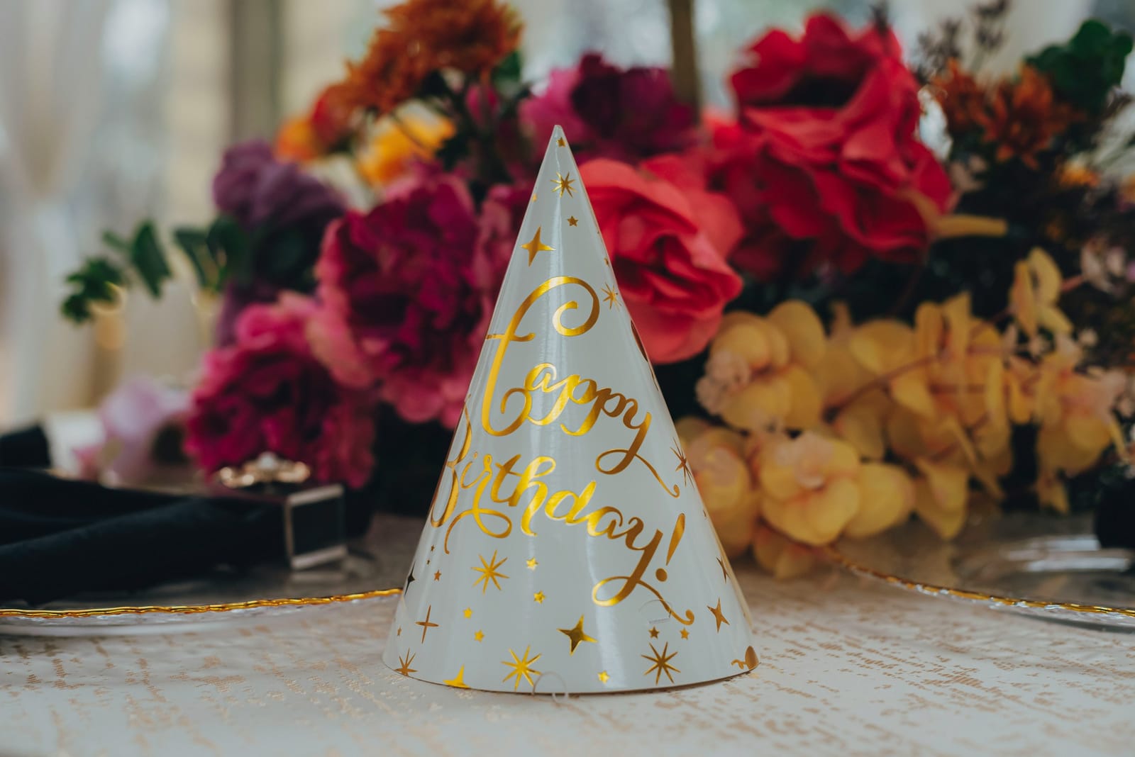 A “happy birthday” party hat among bright flowers.