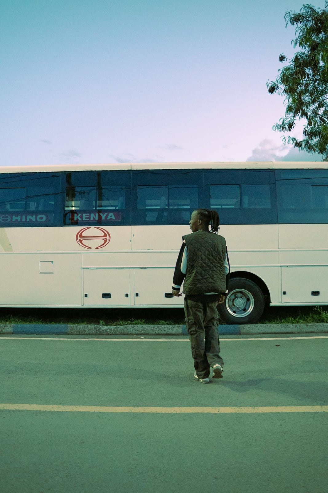 Someone walking toward a Kenya bus on an open road.
