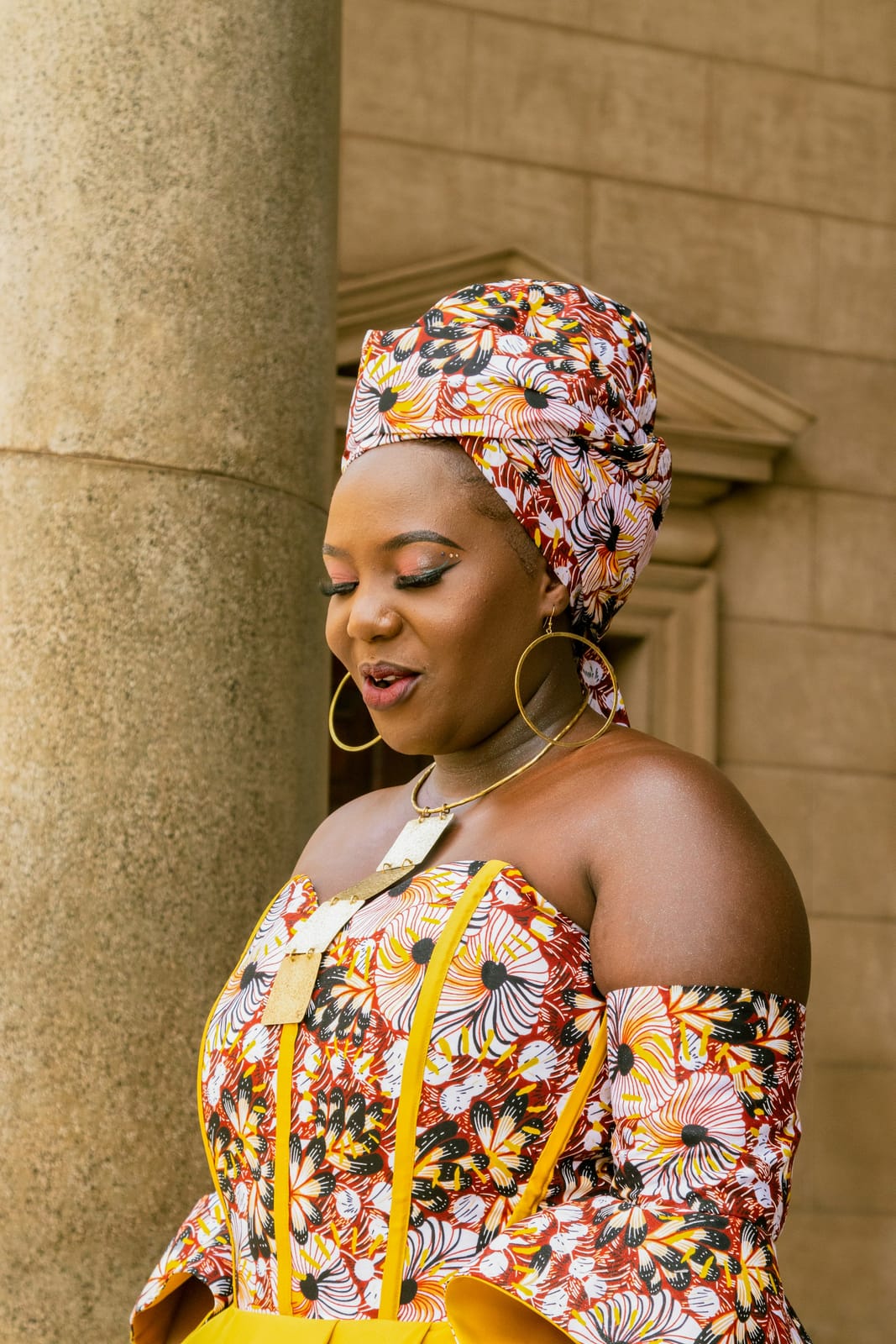 A smiling woman in a headwrap and a floral top.