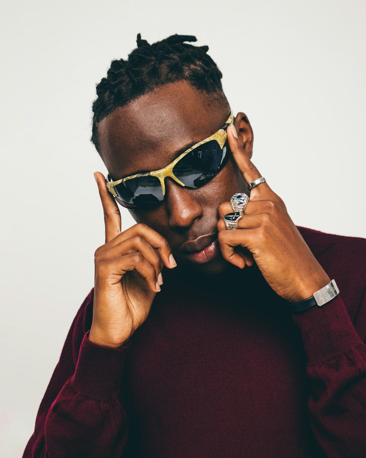 A man in a red sweater adjusting his sunglasses.